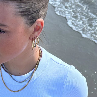 Gold- und silberfarbene Creolen in verschiedenen Größen am Ohr kombiniert, Stylingbeispiel am Strand
