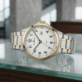 Dugena Boston mit weißem Zifferblatt und silber-goldfarbenem Edelstahlband auf einer Glasfläche mit Spiegelung